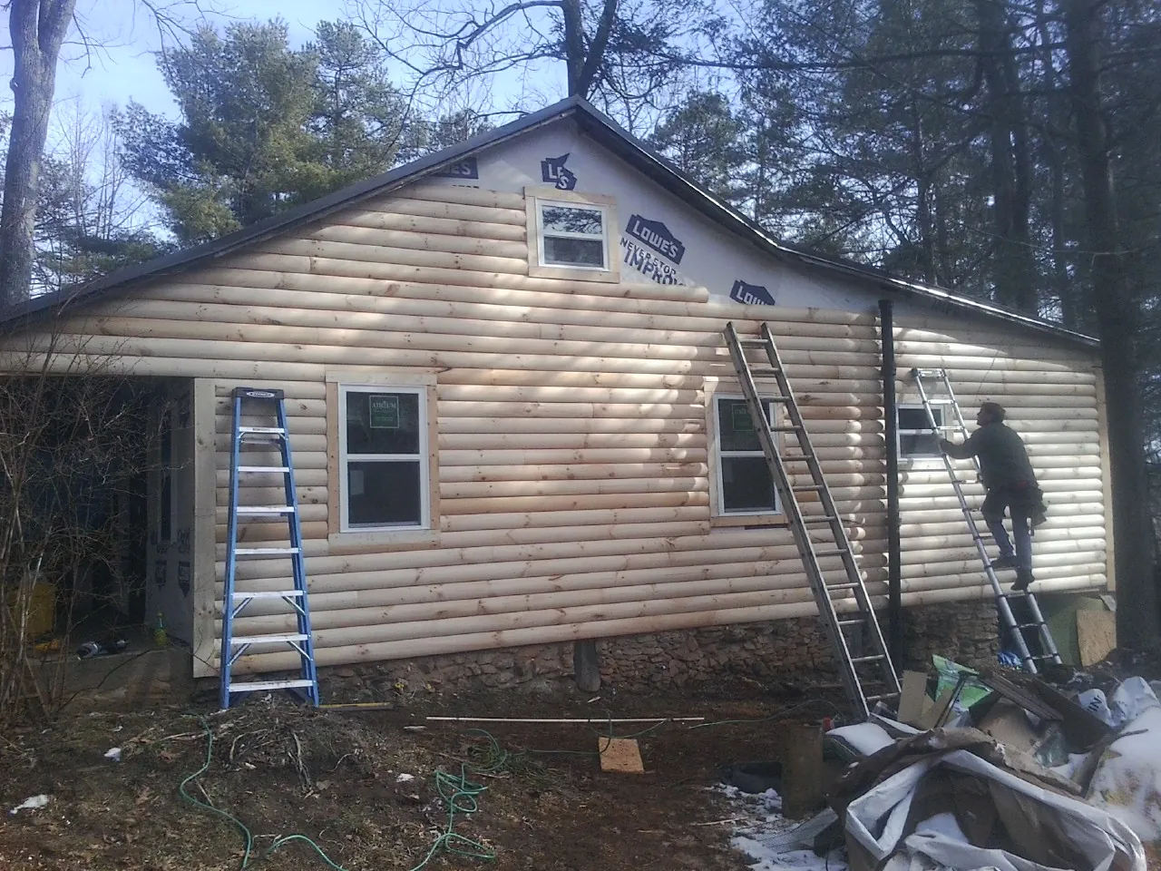 Ladders set against fresh log siding during an exterior remodel in Molt