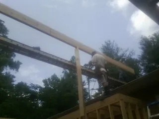 Carpenter setting a ridge beam over a new addition frame — Ice Dam Removal by Roofing Brothers in Molt