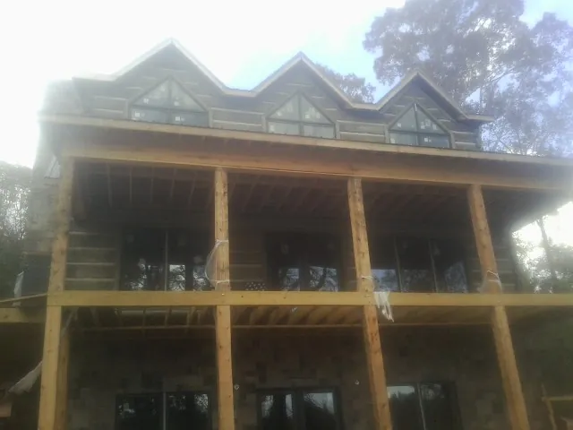 Dormers and porch framing on a large log home under construction — Roof Coating work by our crew in Molt