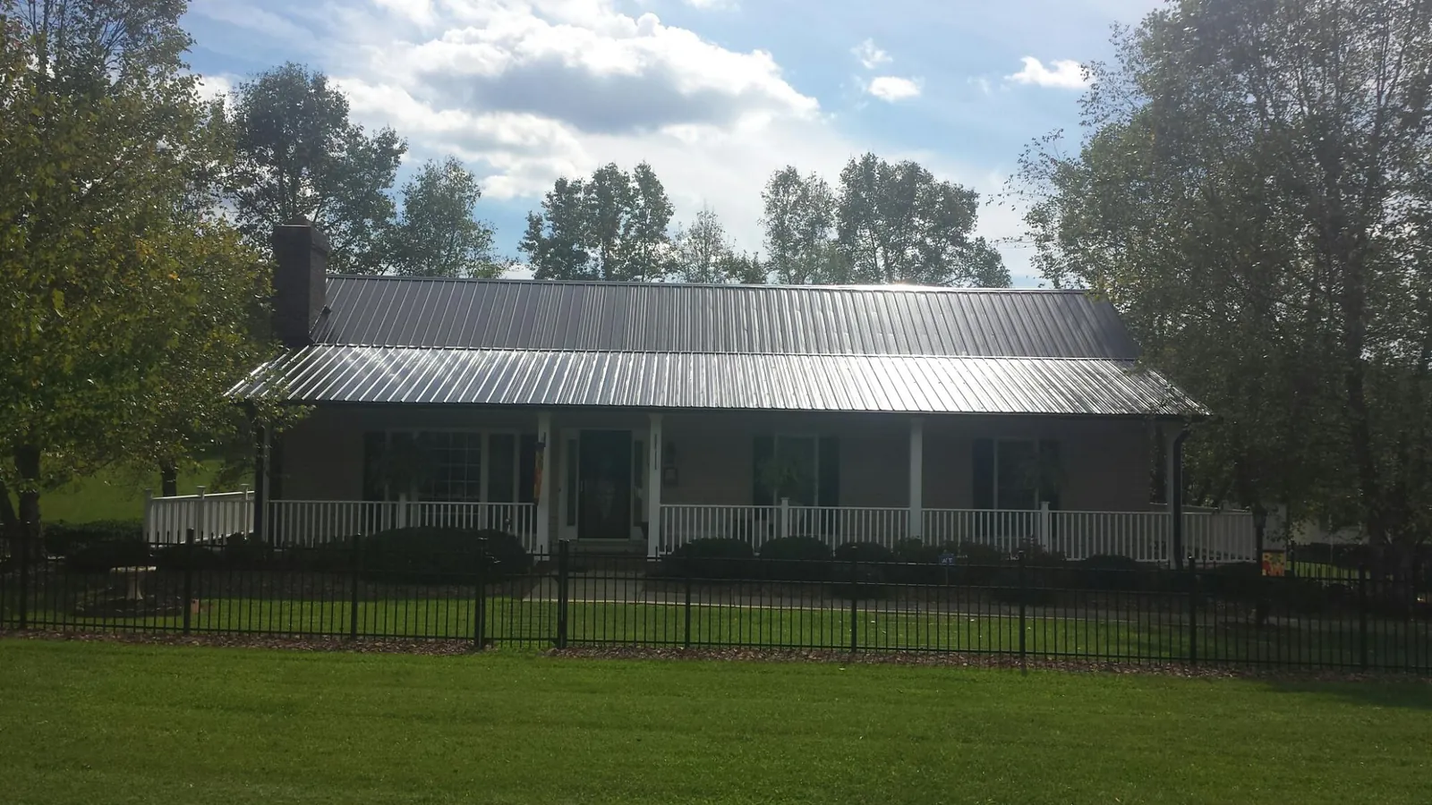 Gray metal roof on a brick ranch with a full width front porch — Gutter Guard Installation work by our crew in Molt