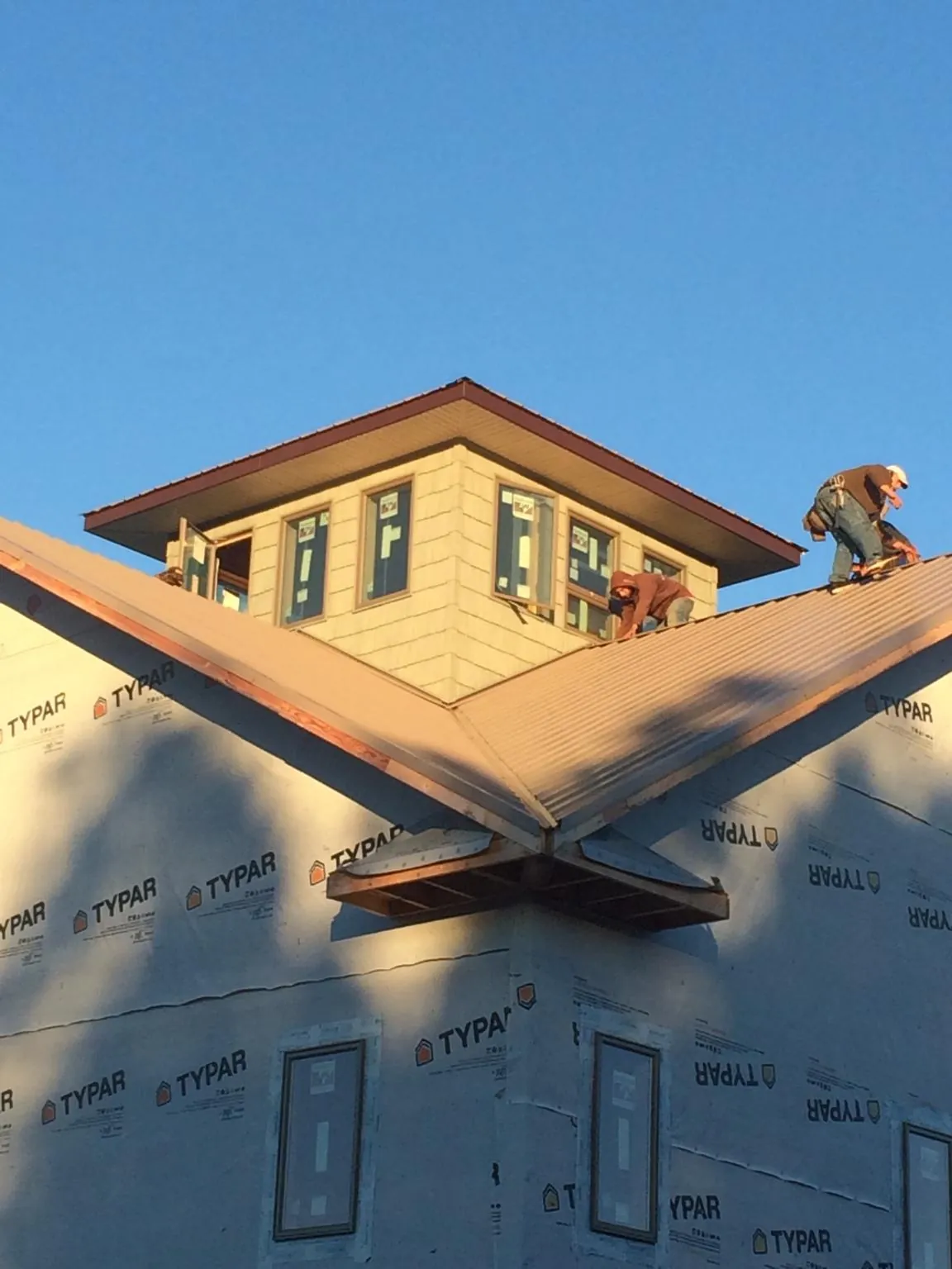 Roofers working around a rooftop cupola on a new metal roof at sunset — Roof Waterproofing in Molt by Roofing Brothers